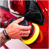 Person using a car polisher on a red car