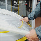 Indasa Cover Roll HDPE Masking Film, technician centering film on car hood. Indasa Academy sign is in the background on window