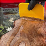 Person applying a MAS Epoxies to wood table with a plastic spreader while wearing gloves.