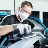 Person sanding a car with protective gear in a workshop setting